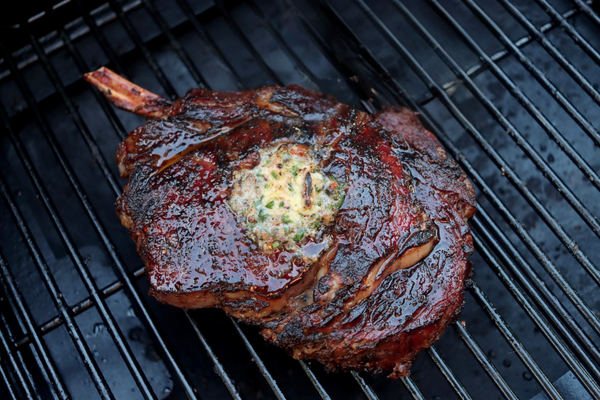 Thick grilled steak sliced on a board beside a two-zone grill