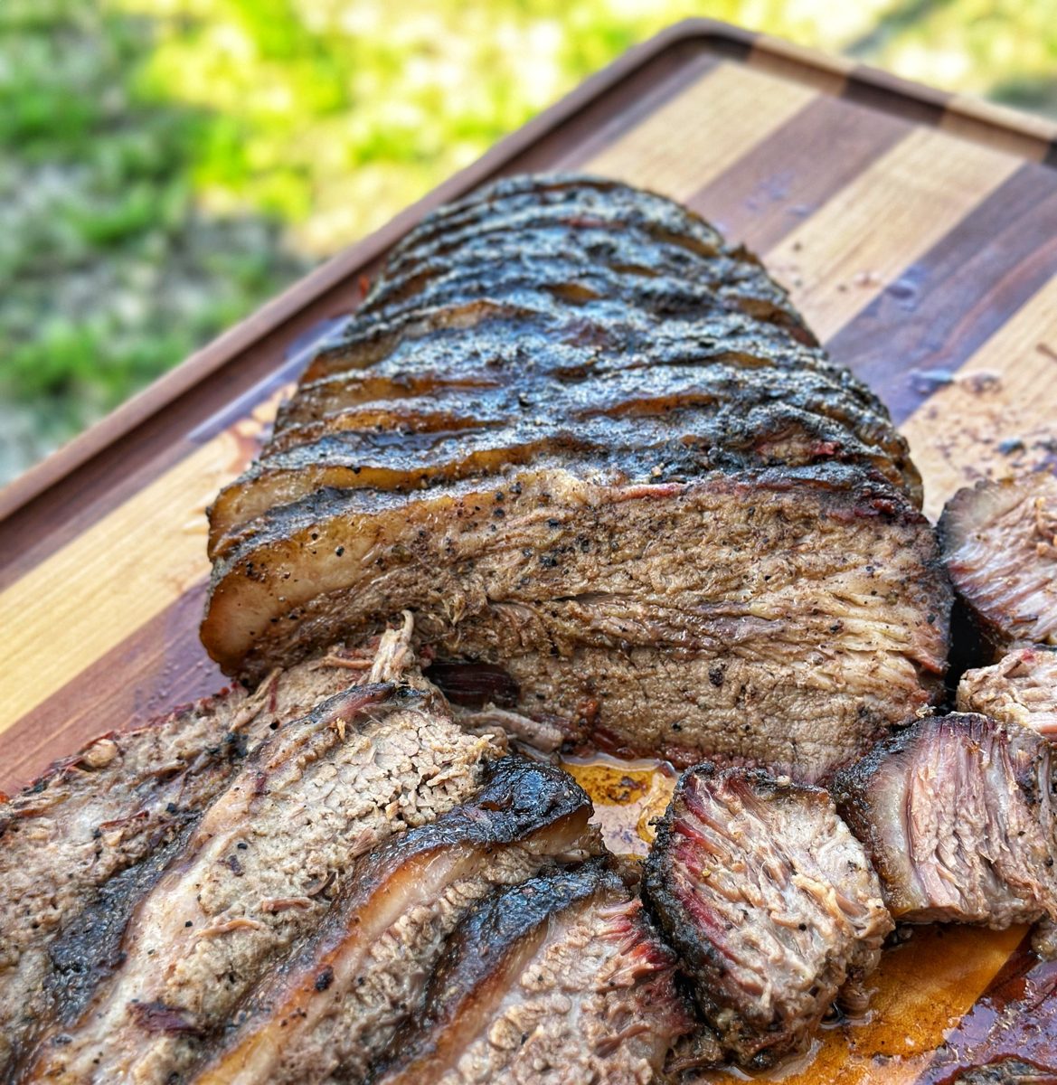 Sliced smoked brisket with a dark pepper bark on a cutting board