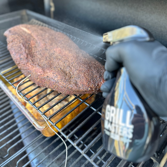 Spray bottle spritzing a brisket on the smoker with apple cider vinegar